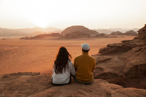 Paar sitzt auf einem Felsen und betrachtet den Sonnenuntergang - PCLF00575
