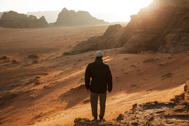 Mann steht auf einem Felsen in der Wüste bei Sonnenaufgang - PCLF00577