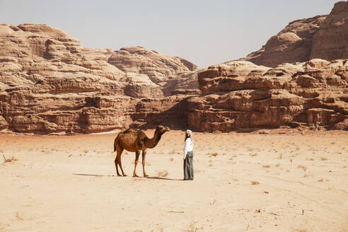 Junge Frau steht vor einem Kamel an einem sonnigen Tag - PCLF00589