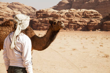 Frau steht an einem sonnigen Tag vor einem Kamel - PCLF00590