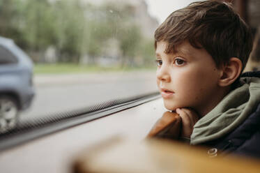 Junge, der mit der Straßenbahn fährt, sitzt am Fenster - ANAF01454