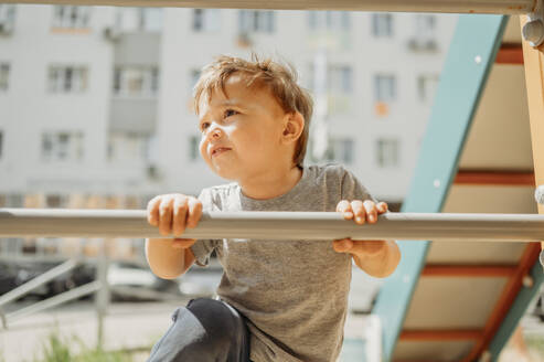 Neugieriger Junge hält Stange und klettert auf dem Spielplatz - ANAF01460