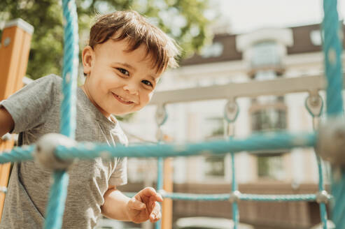 Glücklicher Junge genießt auf dem Spielplatz an einem sonnigen Tag - ANAF01462