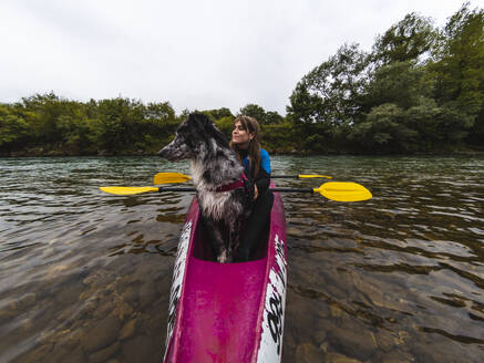 Junge Frau mit Hund sitzt im Kanu auf dem Meer - RSGF00912