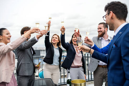 Eine große Gruppe fröhlicher Geschäftsleute feiert eine Party auf der Dachterrasse in der Stadt. - HPIF18530