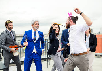 Eine große Gruppe fröhlicher Geschäftsleute feiert eine Party auf der Dachterrasse in der Stadt. - HPIF18539