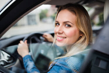 Schöne junge Frau, die im Auto sitzt und hinausschaut. - HPIF18551