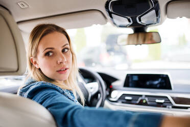 A young woman driver sitting in car, looking back. - HPIF18556