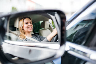 A mirror reflection of young woman driver sitting in car, driving. - HPIF18566