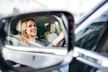 Ein Spiegelbild einer jungen Fahrerin, die im Auto sitzt und fährt. - HPIF18566