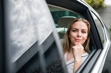 Geschäftsfrau auf dem Rücksitz eines Taxis sitzend, mit Blick nach draußen, Raum kopieren. - HPIF18570