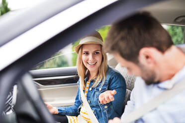 Ein glückliches junges Paar sitzt im Auto und unterhält sich. - HPIF18581