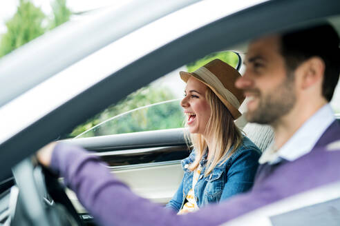 Ein glückliches junges Paar sitzt im Auto und unterhält sich. - HPIF18584