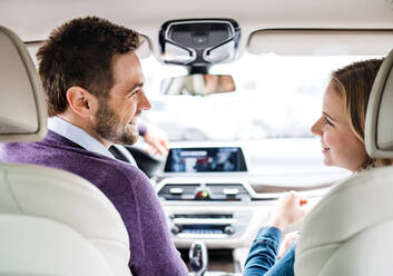 Rückansicht eines glücklichen jungen Paares, das im Auto sitzt und sich unterhält. - HPIF18586