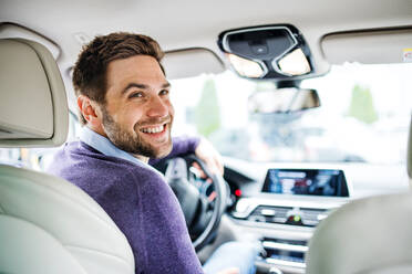 A businessman sitting in brand new car, looking back when driving. - HPIF18587