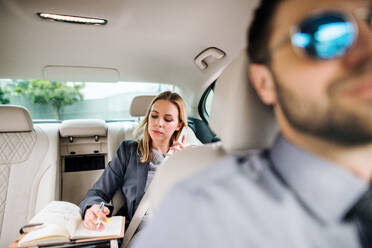 Geschäftsfrau mit Smartphone auf dem Rücksitz eines Taxis sitzend, telefonierend. - HPIF18596