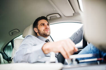 Young businessman with shirt and tie sitting in brand new car, driving. - HPIF18603