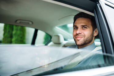 Junger Geschäftsmann mit Kaffee auf dem Rücksitz im Auto. - HPIF18608