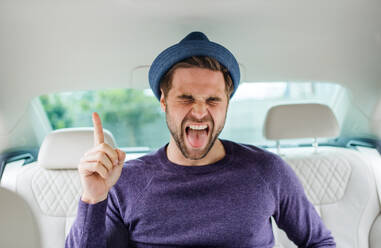 Ein fröhlicher Mann mit Hut sitzt im Auto und hat Spaß. - HPIF18628