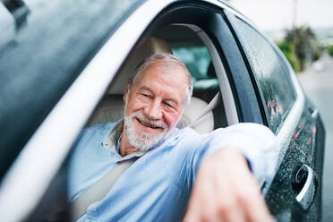 Ein glücklicher älterer Mann sitzt im Auto auf dem Fahrersitz. - HPIF18637
