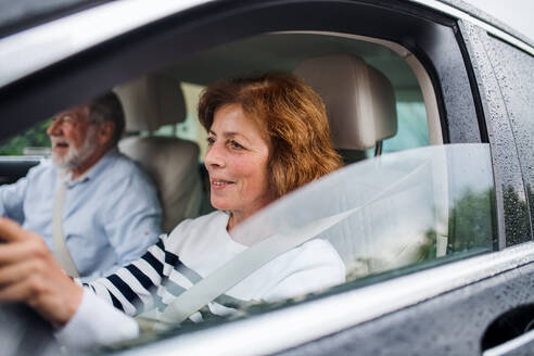 Ein glückliches Seniorenpaar sitzt im Auto, fährt und unterhält sich. - HPIF18646