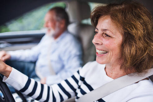 Ein glückliches Seniorenpaar sitzt im Auto, fährt und unterhält sich. - HPIF18647