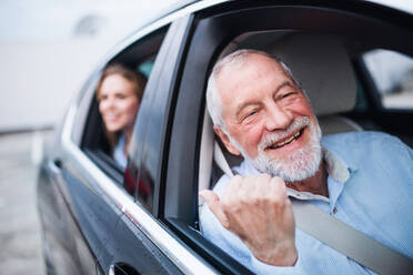 Ein älterer Mann und eine junge Frau sitzen im Auto und schauen aus dem Fenster. - HPIF18662
