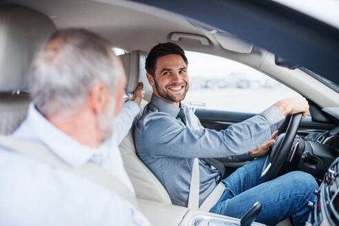 Älterer Vater und Sohn sitzen im Auto, fahren und unterhalten sich. - HPIF18663