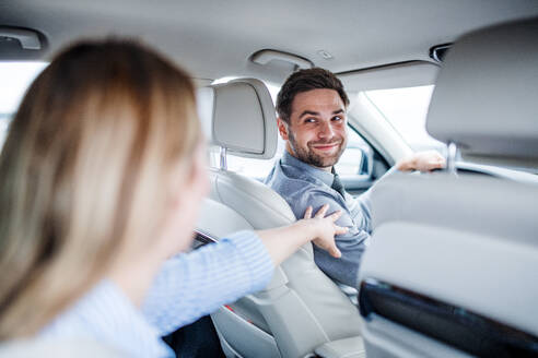 Ein glückliches junges Paar sitzt im Auto und unterhält sich. - HPIF18664