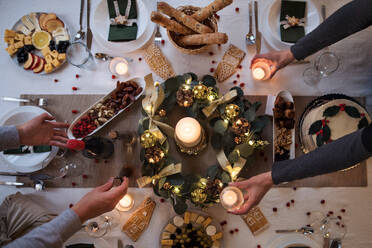 Midsection of unrecognizable couple indoors at home setting the table at Christmas, top view. - HPIF18681