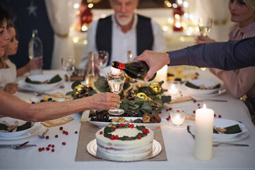 Eine Mehrgenerationen-Familie feiert Weihnachten in einem Haus und schenkt Wein aus. - HPIF18717