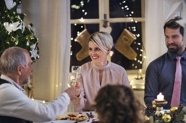 Multi-generation family indoors celebrating Christmas together, clinking glasses. - HPIF18718