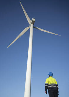 Ingenieur mit Blick auf hohe Windkraftanlage unter Himmel - SNF01669