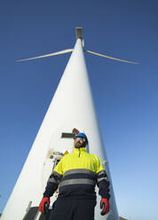 Älterer technischer Ingenieur vor einer großen Windkraftanlage - SNF01677