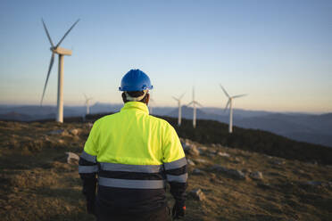 Ingenieur in reflektierendem Anzug bei der Betrachtung von Windkraftanlagen - SNF01689