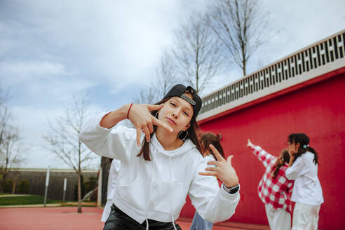 Teenager-Mädchen gestikuliert Horn Zeichen spielen mit Freunden auf dem Spielplatz - MDOF01165