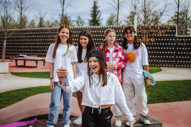 Eine fröhliche Gruppe von Teenagern hält mit ihrem Smartphone ein Selfie auf dem Spielplatz fest - MDOF01177