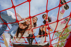 Teenage friends playing on jungle gym at park - MDOF01206