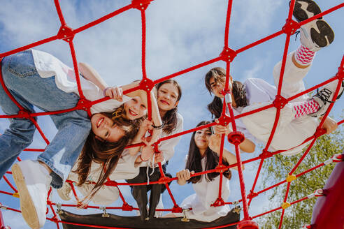 Freunde im Teenageralter spielen auf einem Klettergerüst im Park - MDOF01206