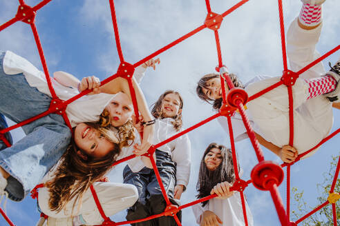 Happy teenage friends playing on jungle gym at park - MDOF01207