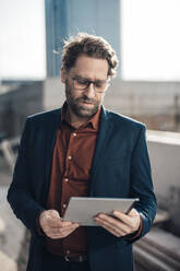 Businessman wearing eyeglasses using tablet PC - JOSEF19278