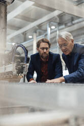 Businessmen examining and operating machinery in factory - JOSEF19286