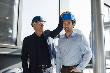 Happy engineers wearing hardhats standing at industry - JOSEF19303