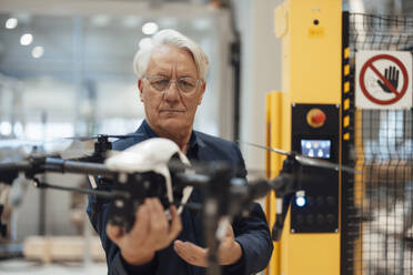 Senior businessman examining drone in industry - JOSEF19323