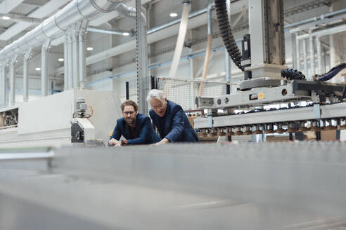 Älterer Geschäftsmann im Gespräch mit einem Kollegen über Maschinen in einer Fabrik - JOSEF19327