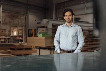 Smiling businessman standing in lumber industry - JOSEF19370