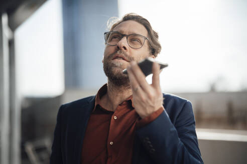 Geschäftsmann mit Brille, der mit einem Smartphone telefoniert - JOSEF19432