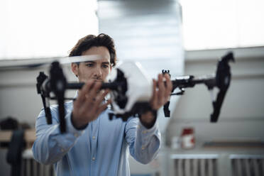 Young businessman examining drone in factory - JOSEF19438