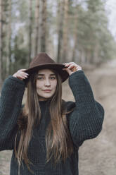 Young woman with long hair wearing hat on field - VBUF00316