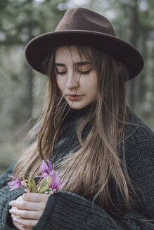 Junge Frau mit langen Haaren hält Blumen - VBUF00317